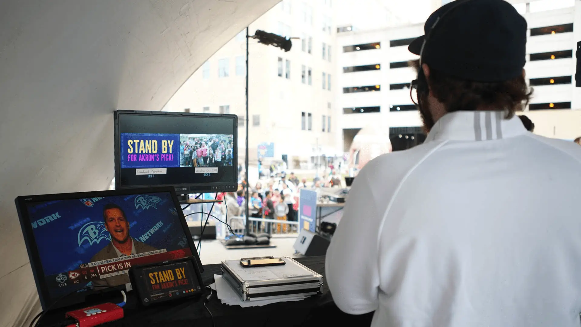 Back of person in headset producing NFL Draft with multiple monitors 