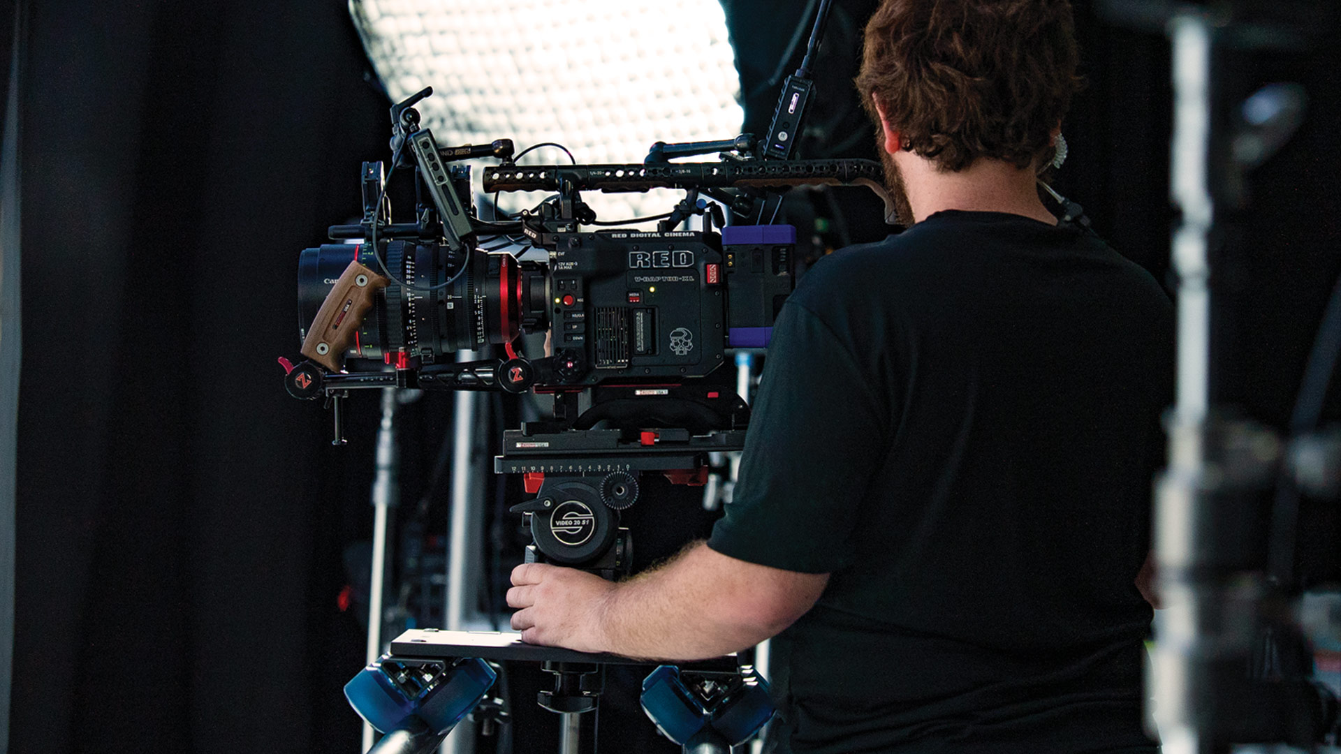 Pritt Entertainment Group Services, man standing next to built up RED V-Raptor XL on dolly rails with film lights in the background