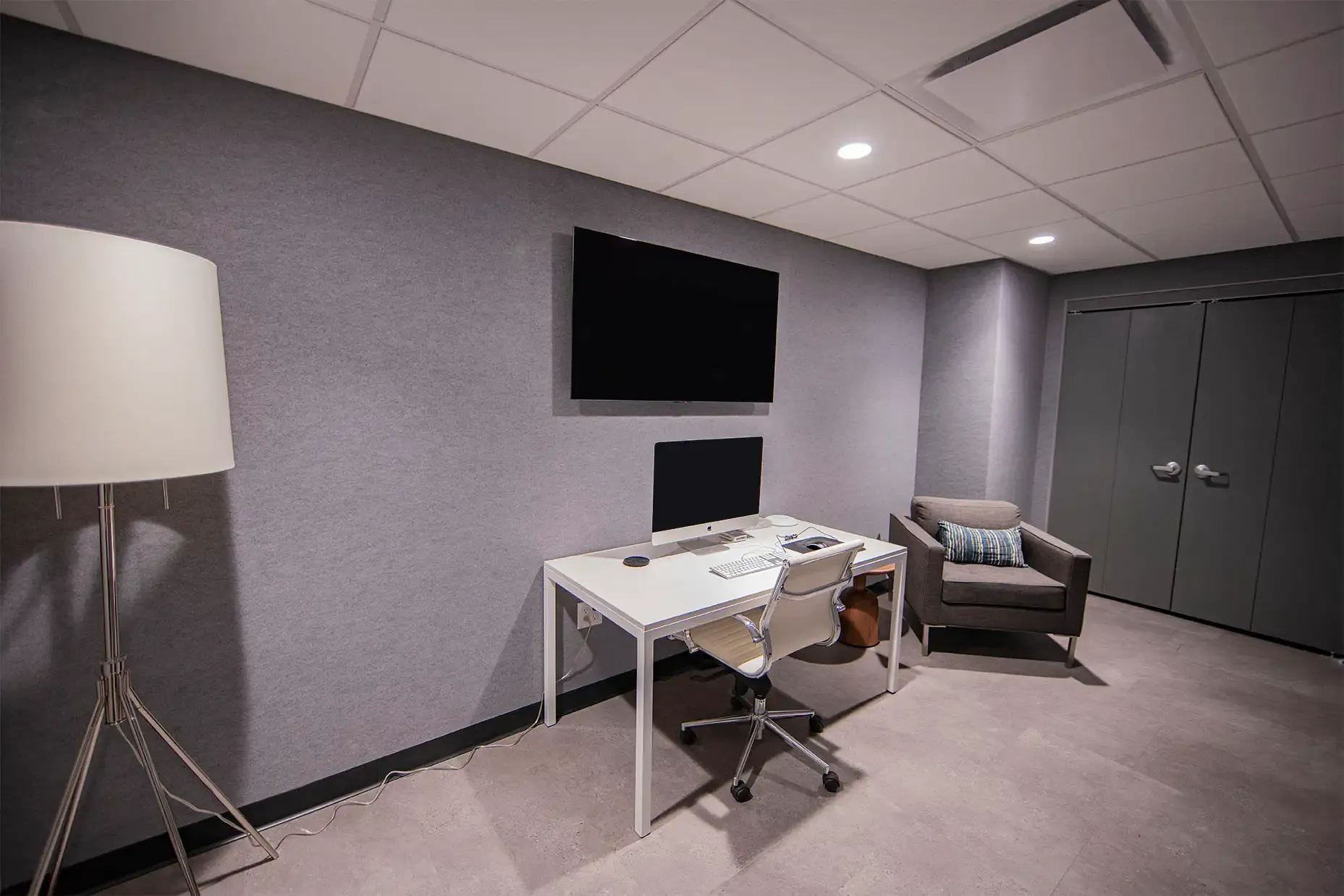 Editing suite with white desk, chair and a tv attached to wall 